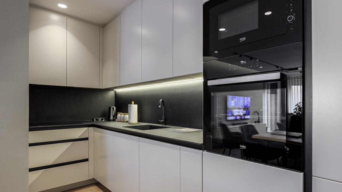 Modern kitchen design with handleless cabinets, black countertop, and backdrop. Includes LED underglow.
