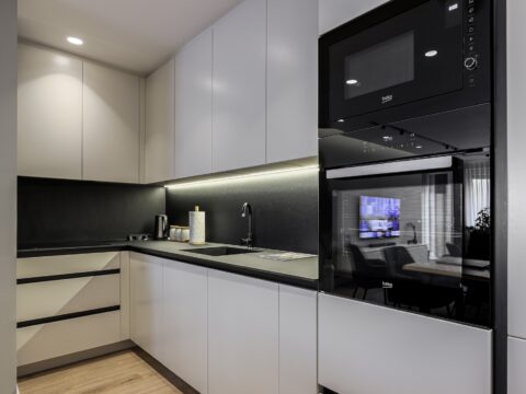Modern kitchen design with handleless cabinets, black countertop, and backdrop. Includes LED underglow.